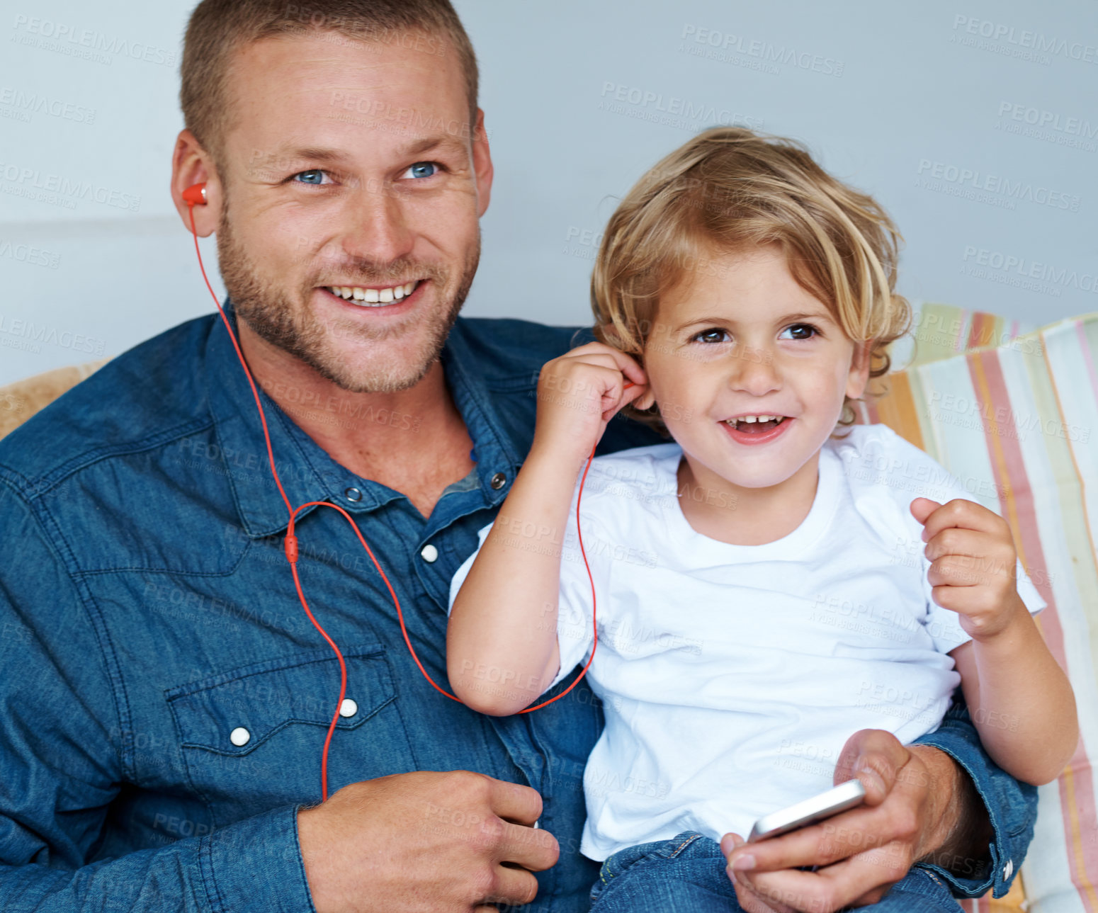 Buy stock photo Shot of an adorable little boy sharing headphones with his father