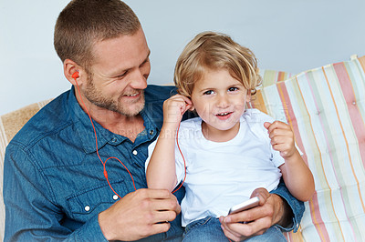 Buy stock photo Shot of an adorable little boy sharing headphones with his father