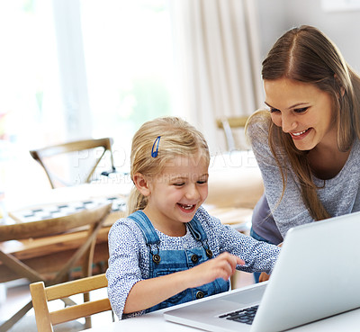 Buy stock photo Shot of a happy mother helping her little girl with the laptop