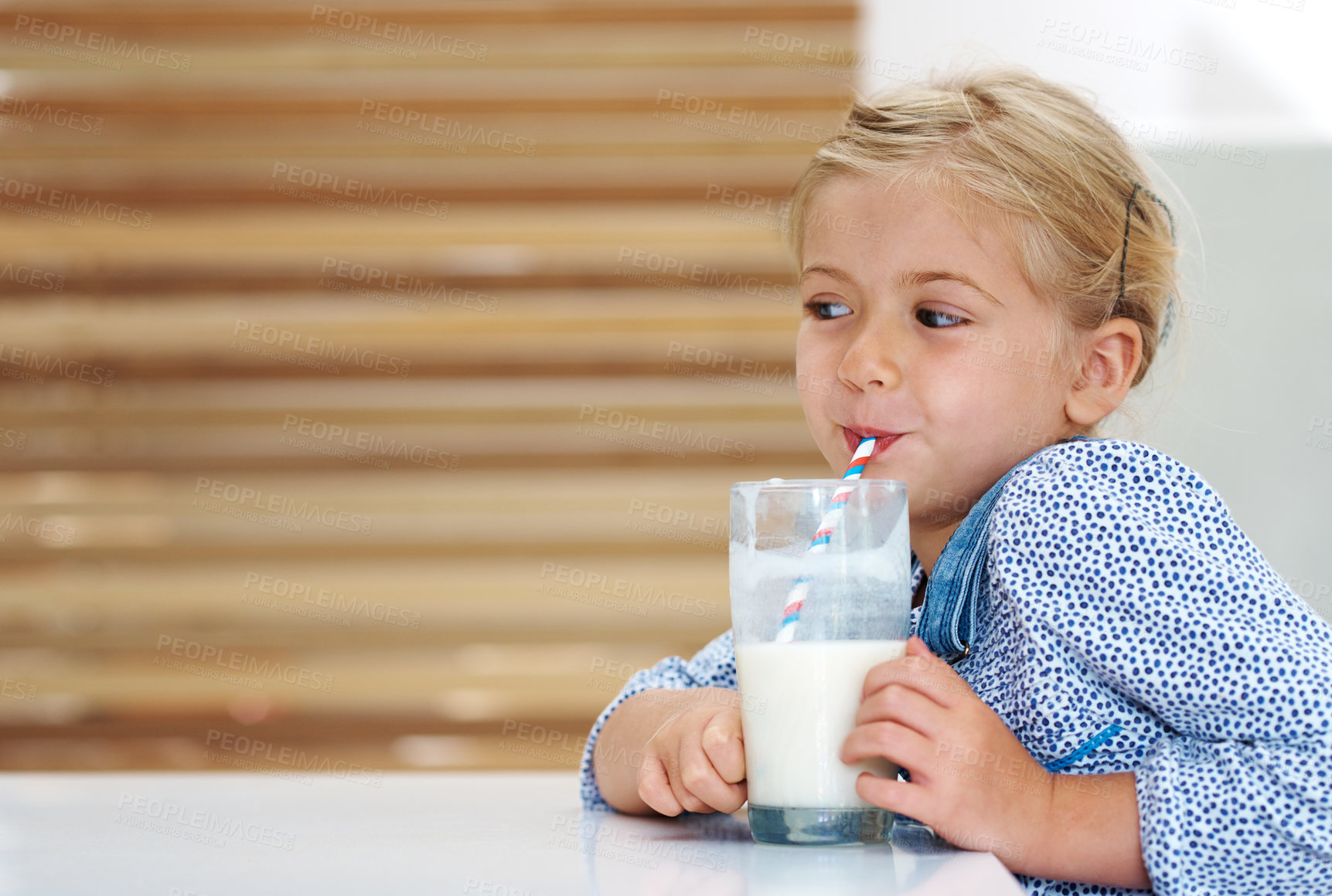 Buy stock photo Girl, child and drinking milk in home, nutrition and vitamin d liquid for brain development. Female person, kid and glass of mineral calcium at kitchen table for thinking, dairy breakfast and ponder