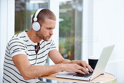 Buy stock photo Shot of a handsome young man working on a laptop outside
