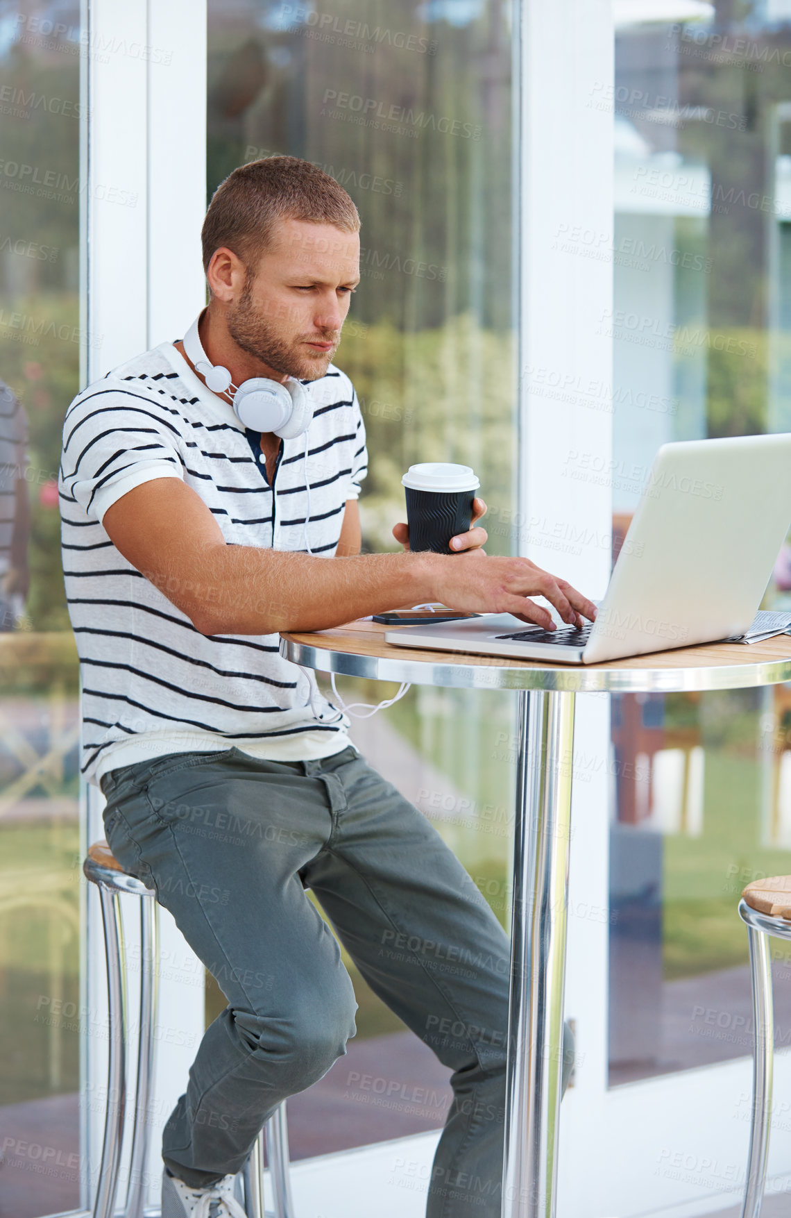 Buy stock photo Coffee, man and typing on laptop in cafe outdoor for remote work, drafting media pitch and press release. Male publicist, headphones and online for managing social accounts or planning campaign.