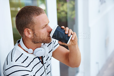 Buy stock photo Shot of a handsome young man drinking coffee outside a cafe