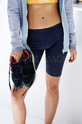 Buy stock photo Cropped shot of a young woman holding a pair of sneakers