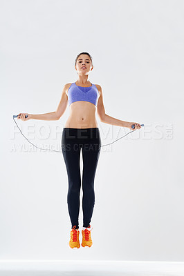 Buy stock photo Girl, skipping rope and jump with portrait in studio for fitness, endurance and agility training or cardio for weightloss. Woman, white background and gym equipment for muscle, workout or exercise.