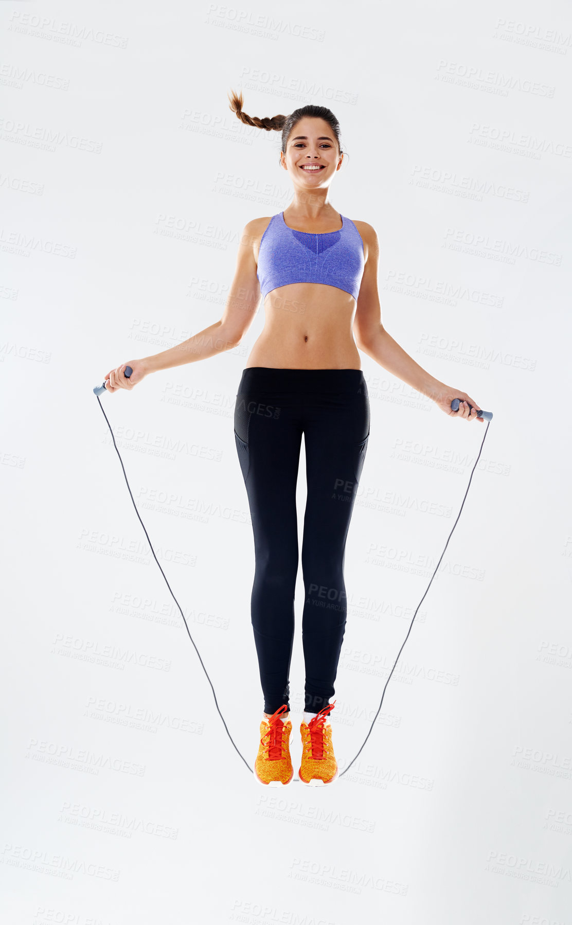 Buy stock photo Woman, skipping rope and jump with portrait in studio for fitness, endurance and agility training or cardio for weightloss. Girl, white background and gym equipment for muscle, workout and low angle.