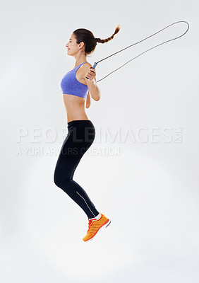 Buy stock photo Woman, skipping rope and profile in studio with jump for fitness with endurance, agility training and energy for weightloss. Girl, white background and gym equipment with action, workout and space.