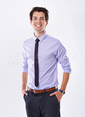 Buy stock photo Studio portrait of a happy handsome young businessman with his hands in his pockets isolated against a white background. Proud male entrepreneur feeling positive and motivated to increase his capital