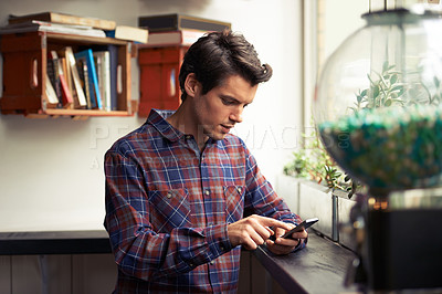 Buy stock photo Handsome man in cafe reading social media on phone and texting. One young ambitious blogger typing a blog post and searching or browsing the internet. Finding interesting activities and gossip online