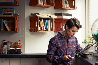 Buy stock photo Man, phone and reading a newspaper at cafe, texting and app for communication at coffee shop. Male person, local news and paper for information at restaurant, headlines article and job search column