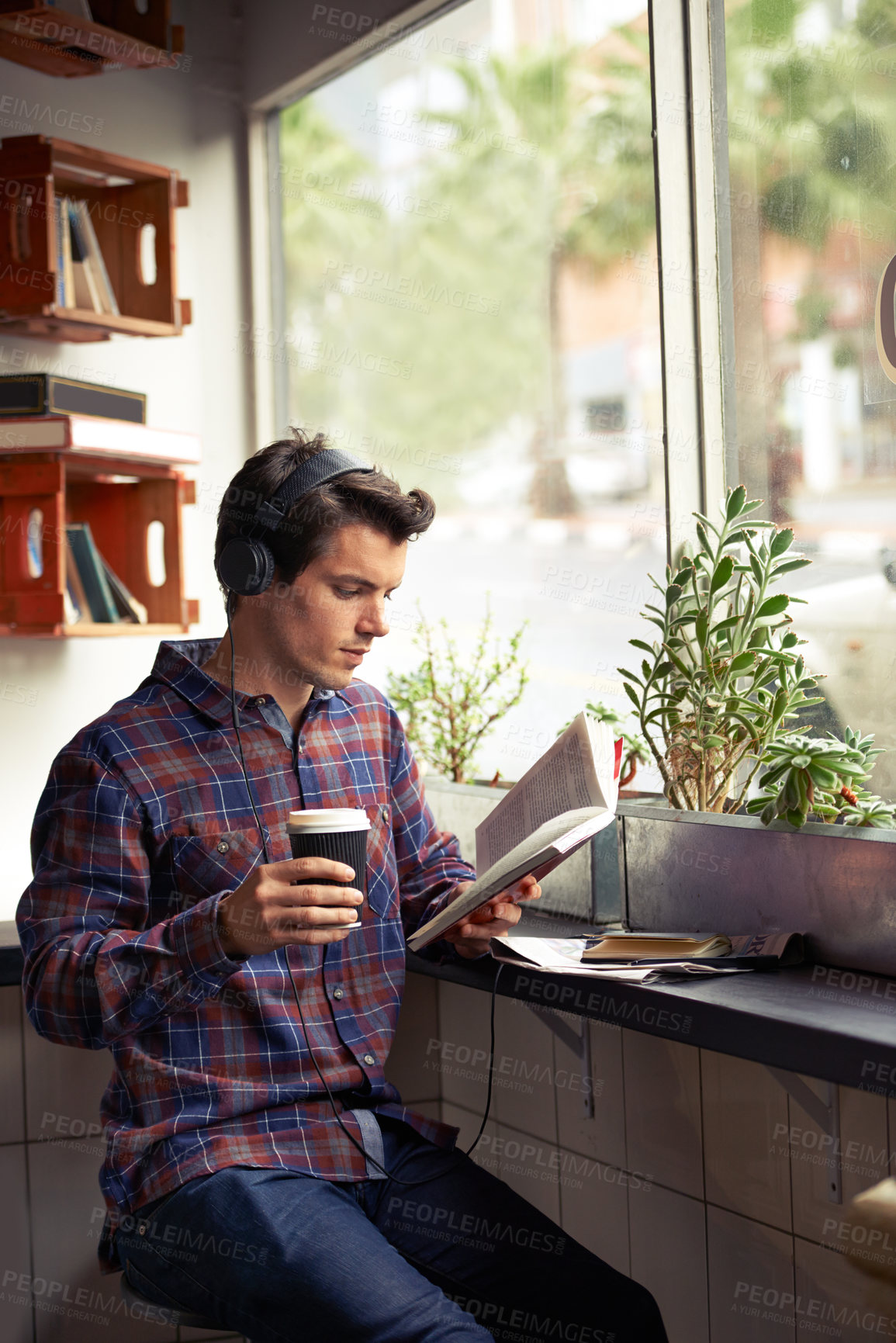 Buy stock photo Man, headphones and coffee for reading book at cafe, literature and student to study on campus. Male person, novel and learning english for journalism at restaurant, espresso and podcast for info