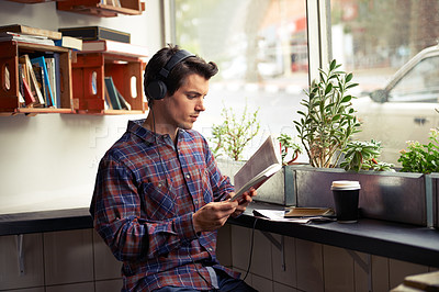 Buy stock photo Man, headphones and music for reading book at cafe, literature and student to study on campus. Male person, novel and learning english for journalism at coffee house, online and podcast for info