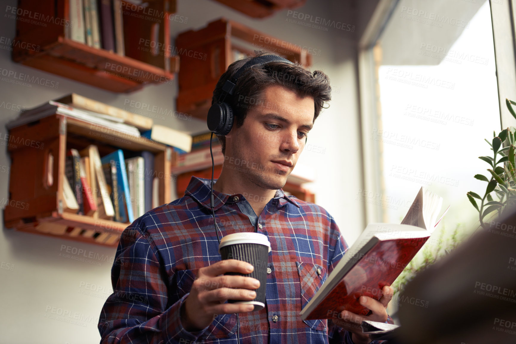 Buy stock photo Man, headphones and tea for book at cafe, literature and student to study on campus. Male person, reading novel and learning english for journalism at coffee house, espresso and podcast for fiction