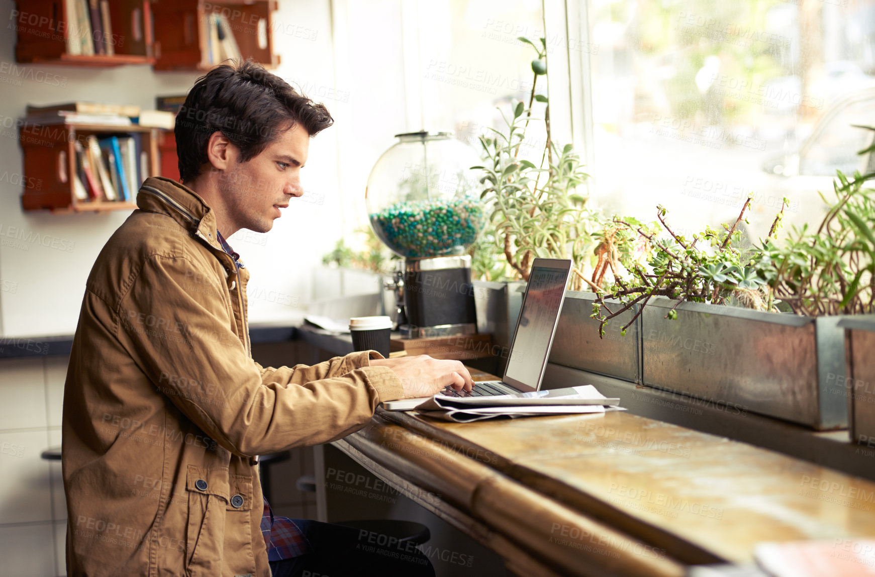 Buy stock photo One ambitious blogger typing on his laptop while sitting alone in a cafe in the morning. Handsome young remote freelancer and entrepreneur using technology to search,  browse internet and read emails