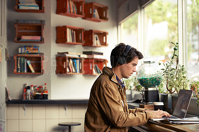 Buy stock photo Student, headphones and man in cafe on laptop for course, college research or music streaming platform. Learning, coffee shop or typing on technology with online network, connection or studying app