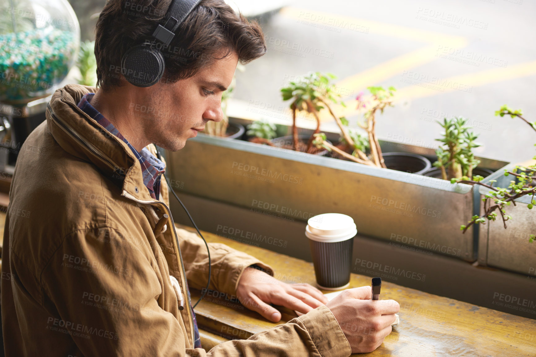 Buy stock photo Headphones, writing and man in cafe with coffee at counter for inspiration, ideas and relax in on break. Music, streaming and creative professional with notes, thinking and drink in trendy restaurant