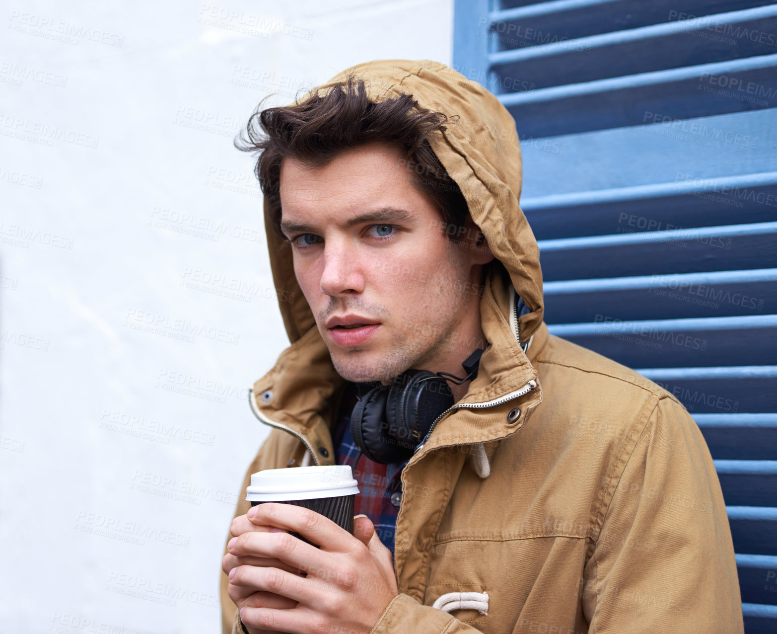 Buy stock photo Man, coffee and portrait at wall with fashion, confidence and headphones for music. Student, take away drink and winter style in city for commute, keep warm and ready for day on street in Europe