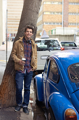 Buy stock photo Man, portrait and coffee in city for fashion, travel and confidence with headphones, tree and car. Male person, latte and happy outdoor by sidewalk for style, cool and trendy in morning in London