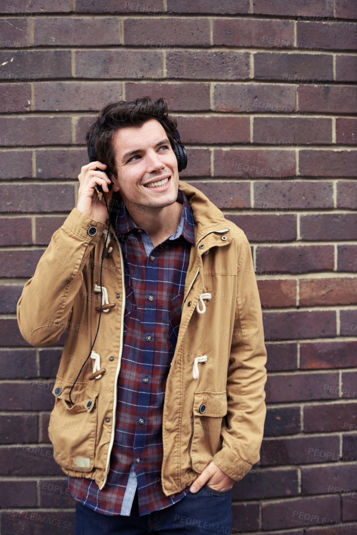 Buy stock photo Shot of a young man standing outdoors using a cellphone on a cold day 