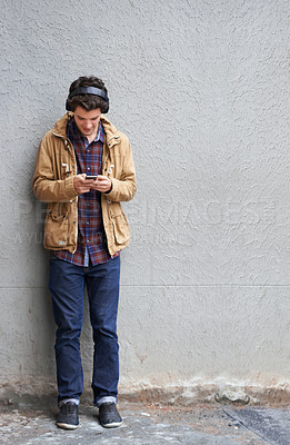 Buy stock photo Space, headphones and man with phone by wall for communication, connection or chat. Mobile, mockup or student texting in city on urban street for music app, social media website or news notification