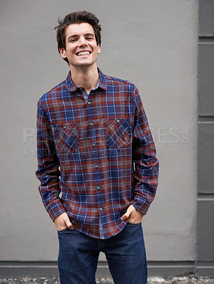 Buy stock photo Portrait, smile and man in city on wall background outdoor for fashion, cool or trendy clothes in Germany. Happy, confidence and person with hands in pockets, streetwear and urban style by building