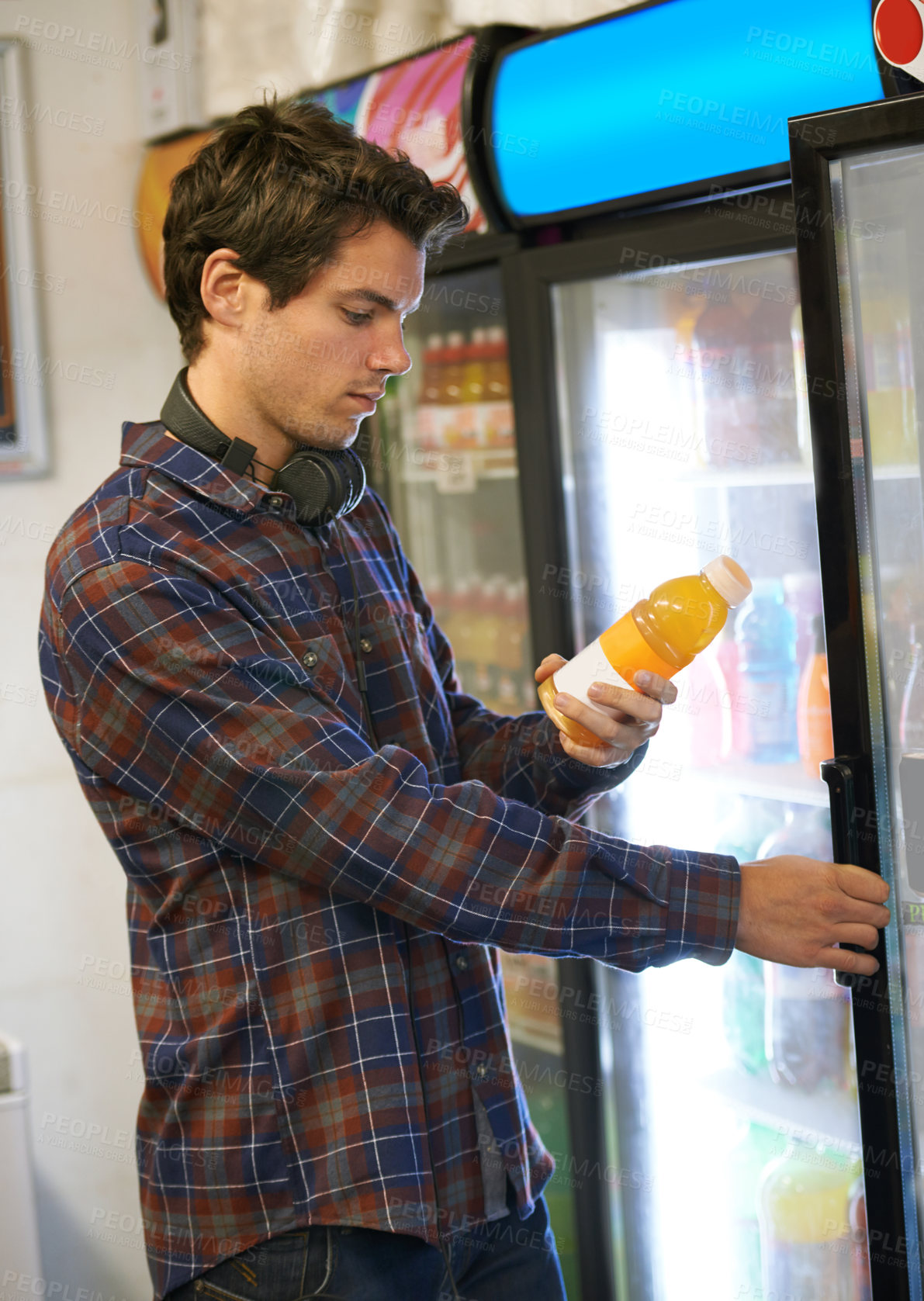 Buy stock photo Man, fridge and shopping in shop for juice, soda and decision with headphones, label and reading. Student, refrigerator and choice in supermarket or convenience store as customer for drinks by door