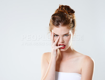 Buy stock photo Cropped studio portrait of a beautiful young woman biting her finger flirtatiously