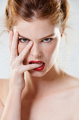 Buy stock photo Cropped studio portrait of a beautiful young woman biting her finger flirtatiously