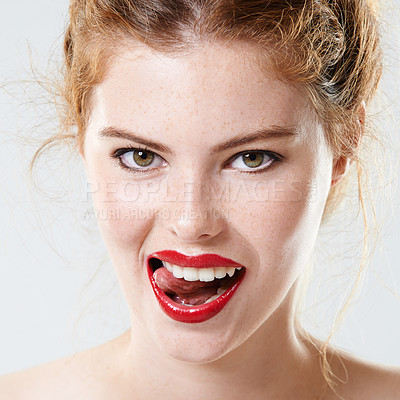 Buy stock photo Closeup studio portrait of a beautiful young woman wearing red lipstick biting her tongue