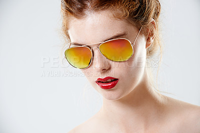 Buy stock photo Cropped studio portrait of a beautiful young woman wearing red lipstick and retro sunglasses
