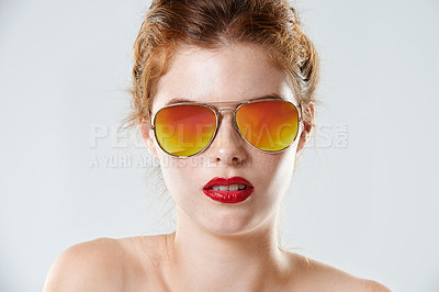 Buy stock photo Cropped studio portrait of a beautiful young woman wearing red lipstick and retro sunglasses
