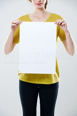 Buy stock photo Woman holding a blank marketing poster and endorsing with advertising, branding and promotion sign. Presenting sales deal. Model standing alone, isolated against grey studio background with copyspace