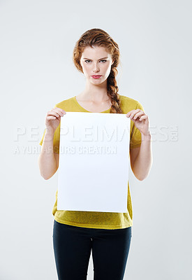Buy stock photo Cropped studio portrait of an attractive young woman holding up a white placard with copyspace