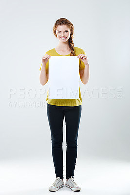 Buy stock photo Full-length studio portrait of an attractive young woman holding up a white placard with copyspace