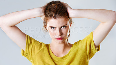 Buy stock photo Studio shot of an attractive young woman pouting while standing with her hand in her hair