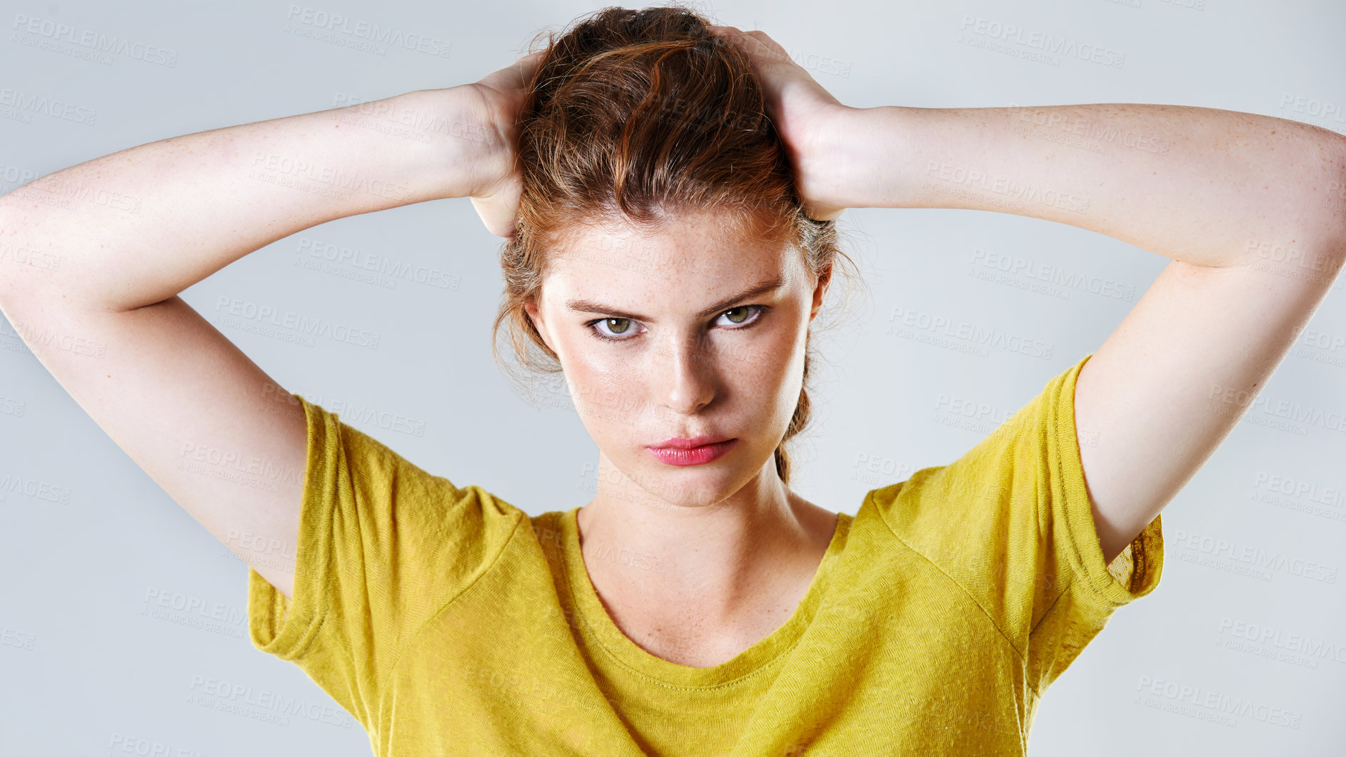 Buy stock photo Studio shot of an attractive young woman pouting while standing with her hand in her hair
