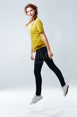 Buy stock photo Studio portrait of a beautiful young woman in casualwear jumping against a gray background