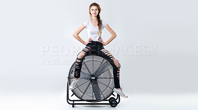Buy stock photo Studio portrait of an attractive young woman sitting on top of a large electric fan