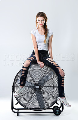 Buy stock photo Studio portrait of an attractive young woman sitting on top of a large electric fan