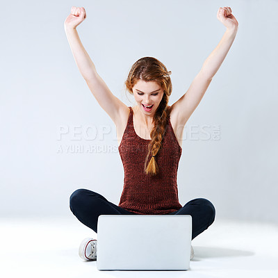 Buy stock photo Studio shot of an excited young woman sitting with her laptop on the floor