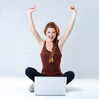 Buy stock photo Studio portrait of an excited young woman sitting with her laptop on the floor