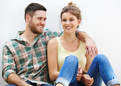 Buy stock photo Shot of a loving young couple sitting beside each other at home