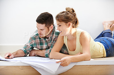 Buy stock photo Shot of a young couple inspecting the building plans for their new home