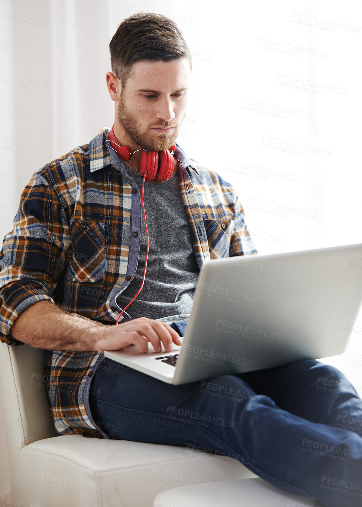 Buy stock photo Man, headphones and typing with laptop on chair for music software, audio or content creation at home. Young, male person or musical artist with headset on computer for digital sound track or app