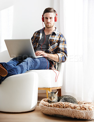 Buy stock photo Man, home and cat on laptop with headphones for editing videos as videographer with remote work. Male person, employee and serious on portrait as freelancer for audio, music and streaming service