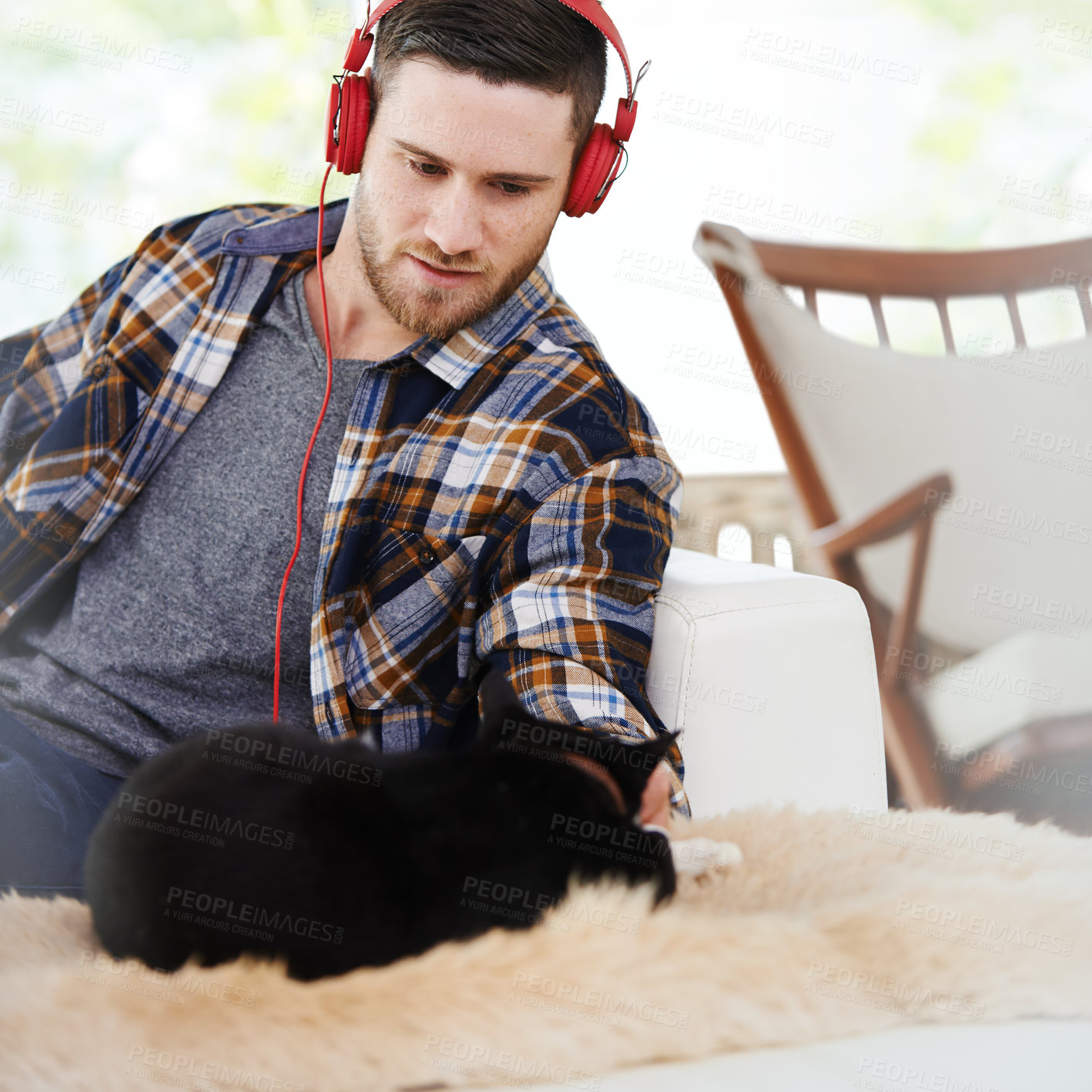 Buy stock photo Man, headphones and cat in living room with music, animal and podcast to relax on the weekend at home. Pet, streaming and internet radio with calm track in chair with digital and online listening