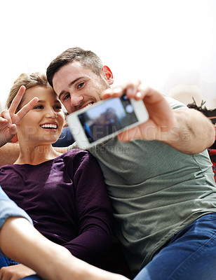 Buy stock photo Shot of a young couple taking a selfie together while relaxing at home