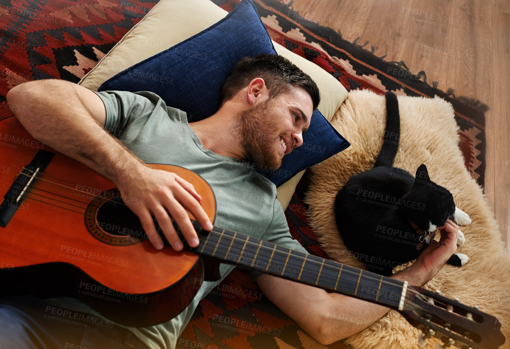 Buy stock photo Man, cat and guitar in apartment for relax, bonding or music together on floor with blanket or pillow. Male person, pet and playing instrument in home for connection, musician or comfort with support