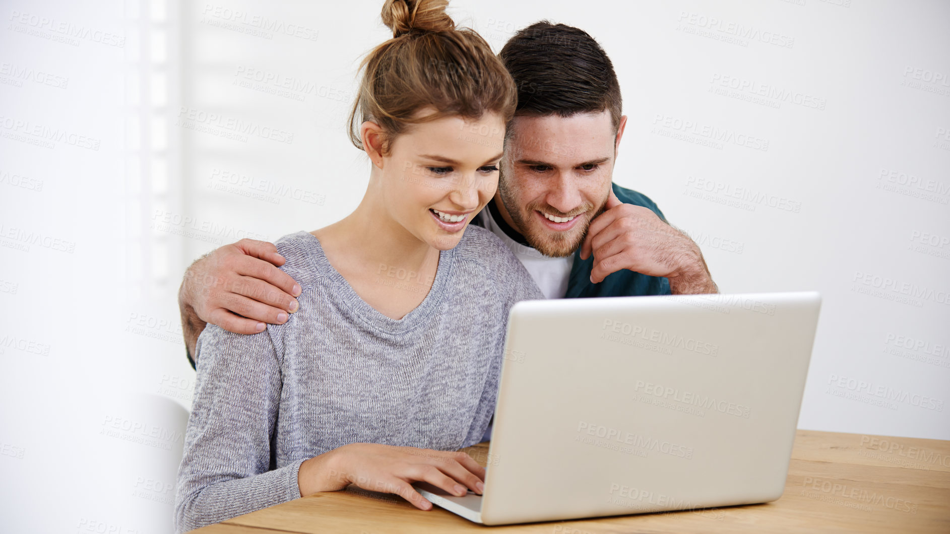 Buy stock photo Shot of a happy young couple using a laptop while relaxing at home together