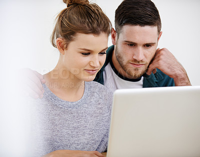 Buy stock photo Shot of a young couple using a laptop while relaxing at home together